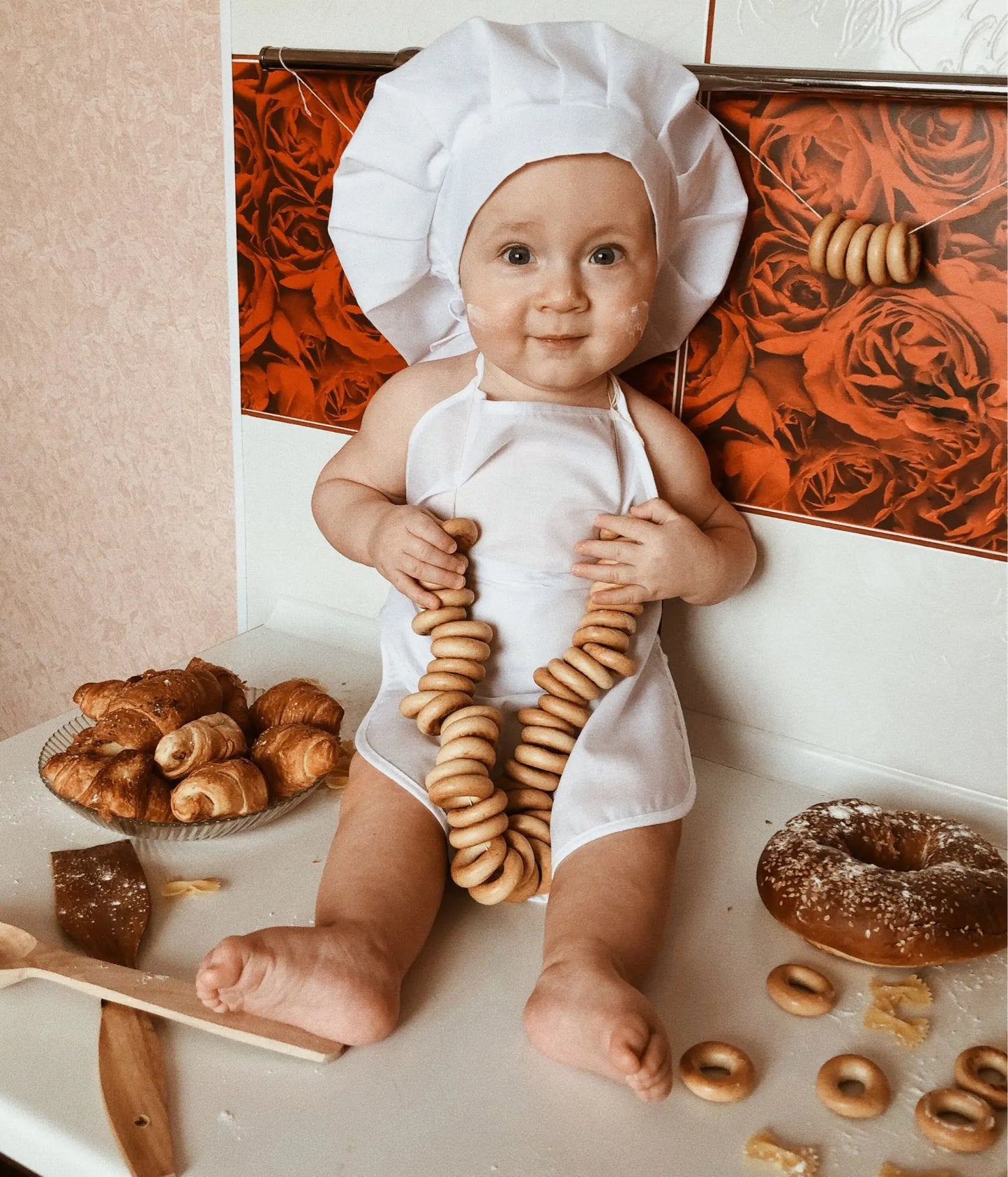 tablier de cuisine bébé assis sur un comptoir avec des pâtisseries